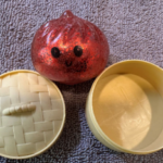 Recalled red Squishy Dumpling water bead toy next to its tan container, ABC Trading model 3655, CPSC recall October 2026