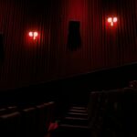 Dark red theater atmosphere illustrating American Horror Story Season 13