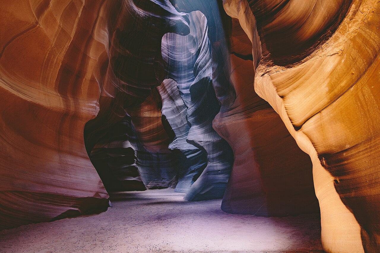Real photograph of curved red-orange sandstone walls lit by natural sunlight inside Antelope Canyon near Page, Arizona
