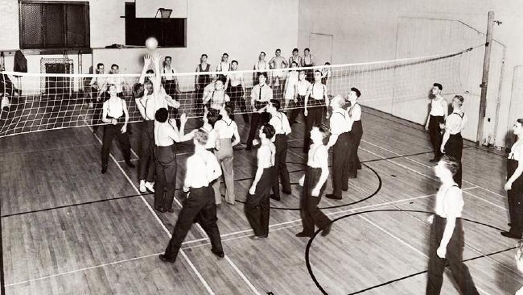 Authentic historical photograph of players in an indoor volleyball game in 1910, after the original Mintonette period