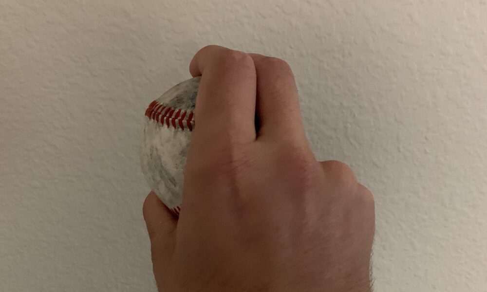 Real photograph of fingers holding a baseball in a curveball grip