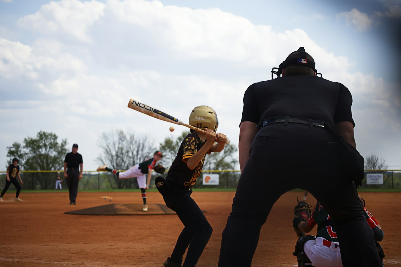 A real Little League youth baseball game with batter and umpire watching the pitch