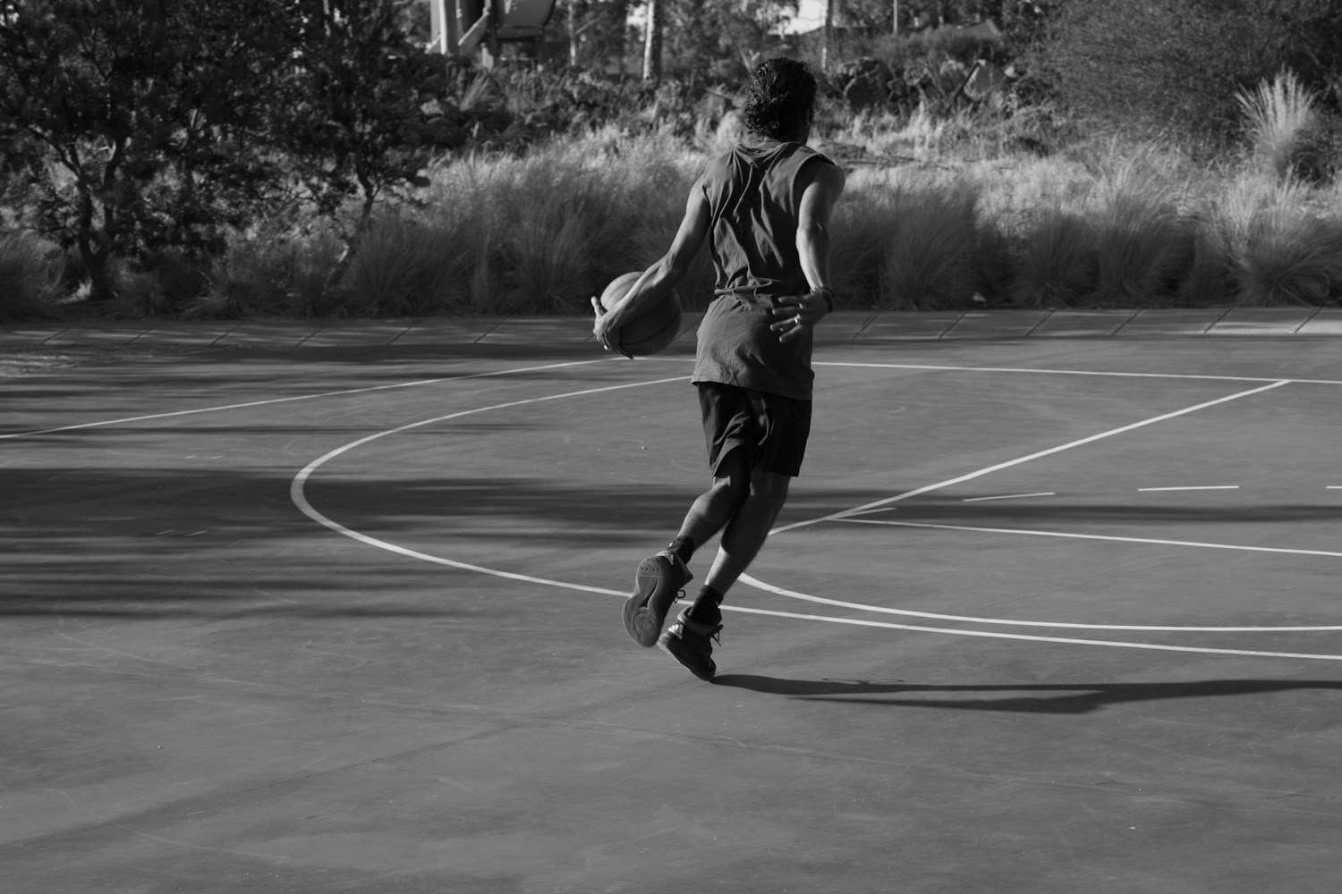 Basketball player practicing dribbling on an outdoor court