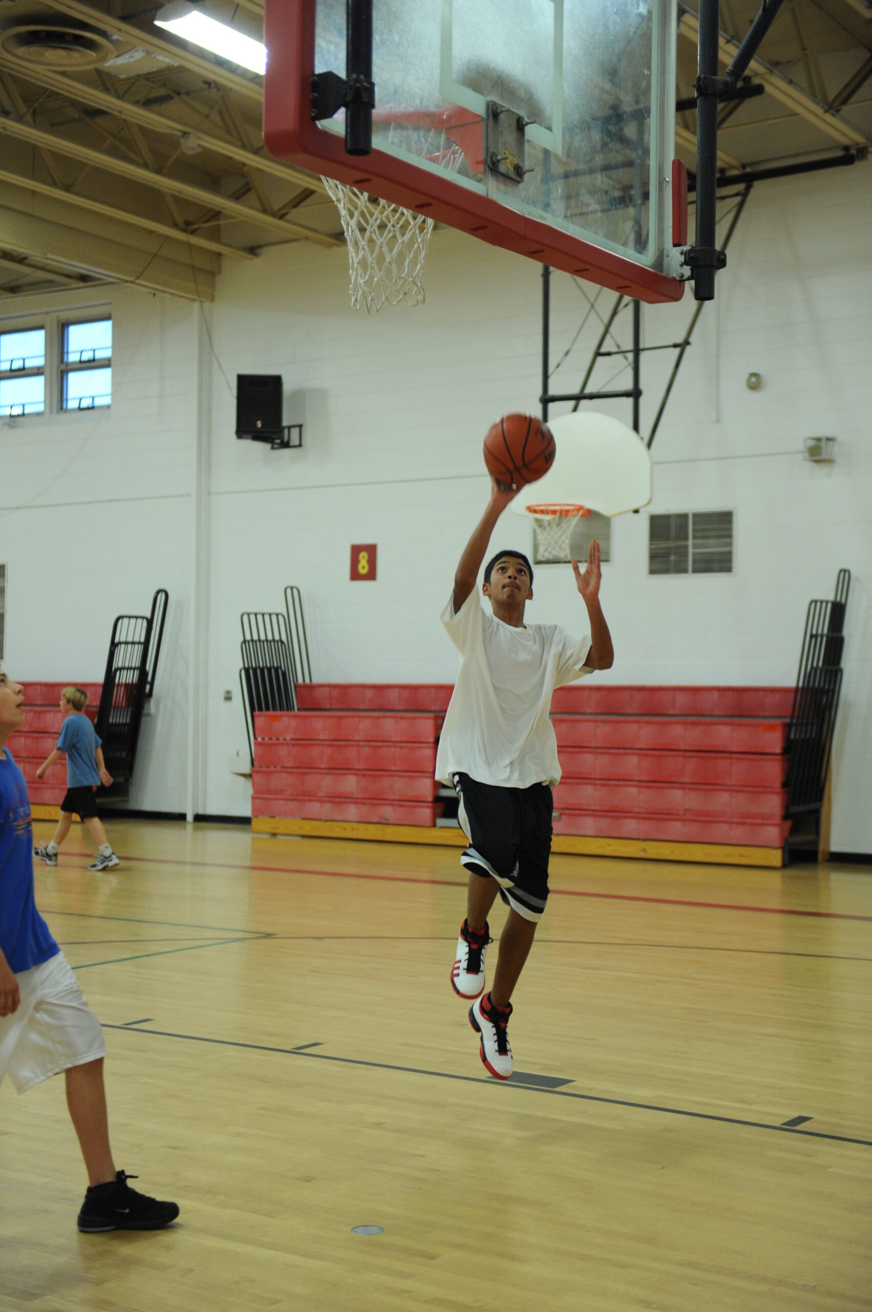 Youth basketball player practicing a layup under the hoop during team training