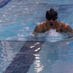 Athlete performing the breaststroke while surfacing to breathe in an indoor swimming pool