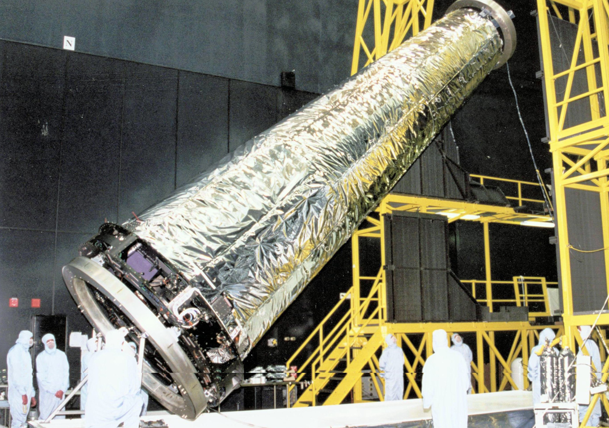 Real Chandra X-ray telescope assembly being positioned in a cleanroom before launch, with technicians and a suspended mirror system