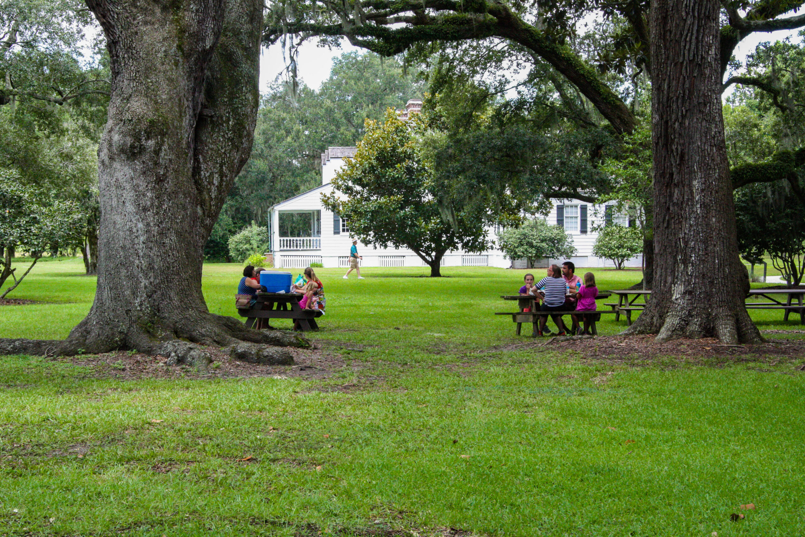 Visitors resting under trees beside the Snee Farm house at Charles Pinckney National Historic Site