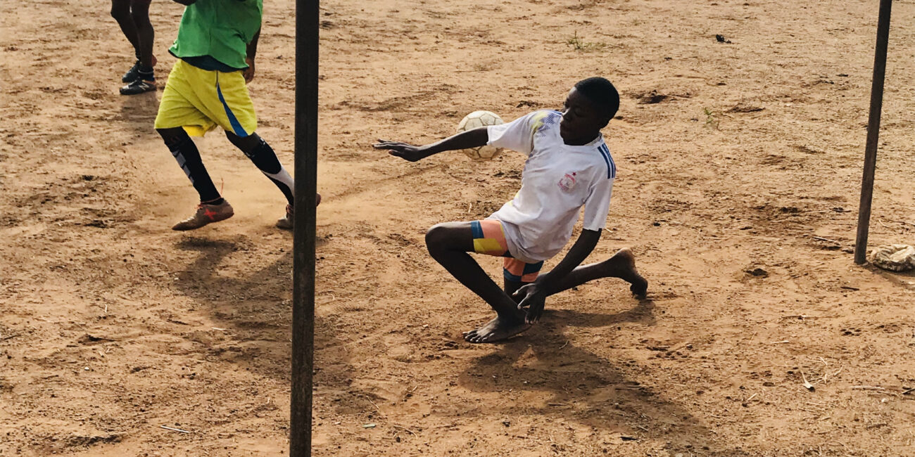 Football goalkeeper saving an incoming shot during a match, illustrating the aim of a clean sheet