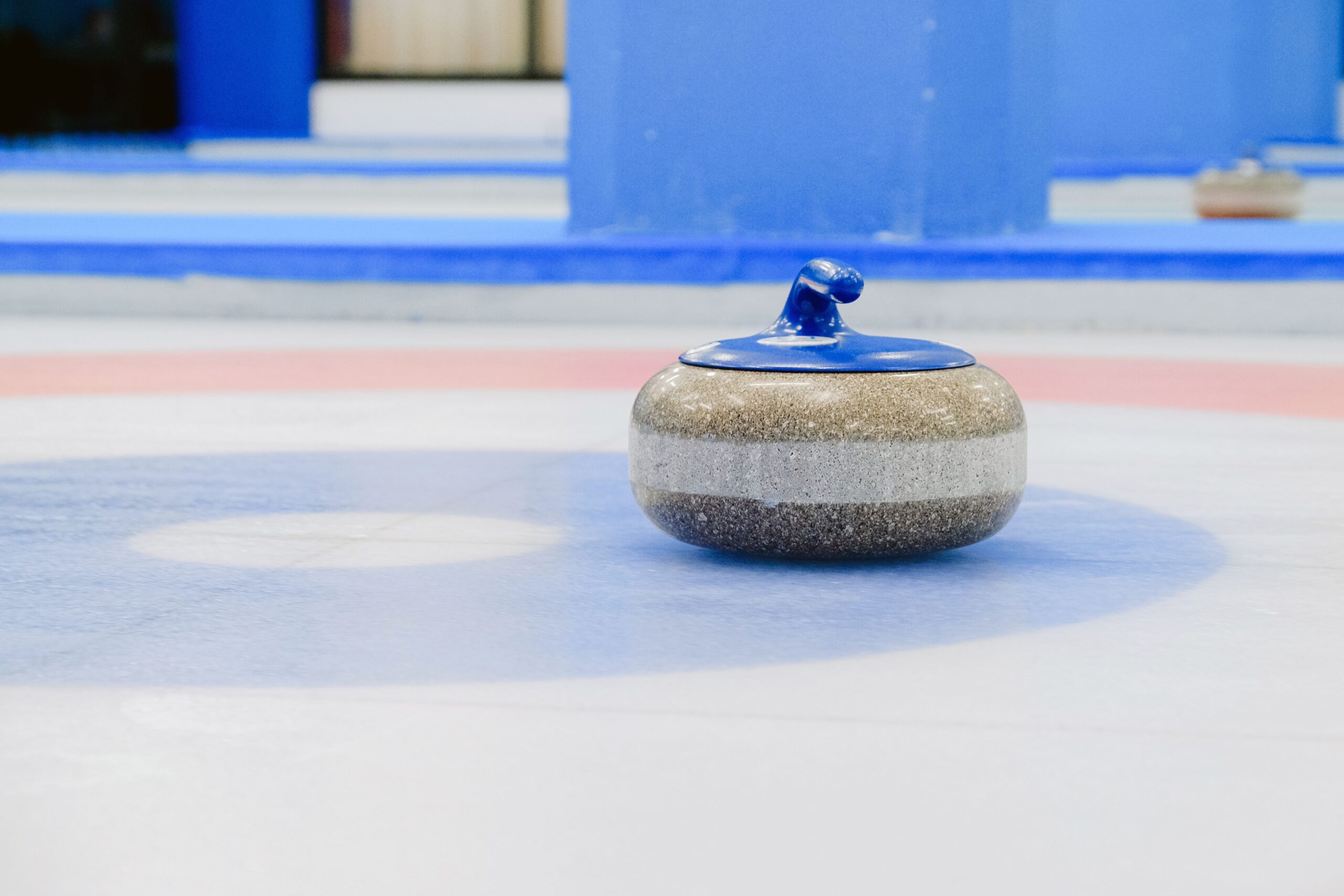 Authentic curling stone placed on the house target on an indoor ice sheet, showing the concentric scoring rings