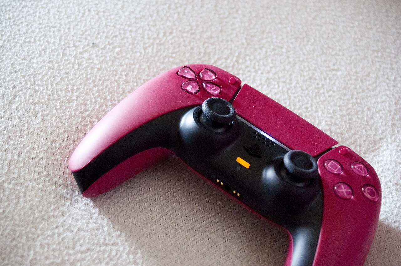 Red and black PlayStation 5 DualSense wireless controller with its pairing buttons visible