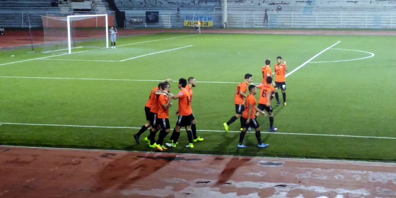 Soccer players celebrating a goal together on a football field, illustrating goal-scoring terms