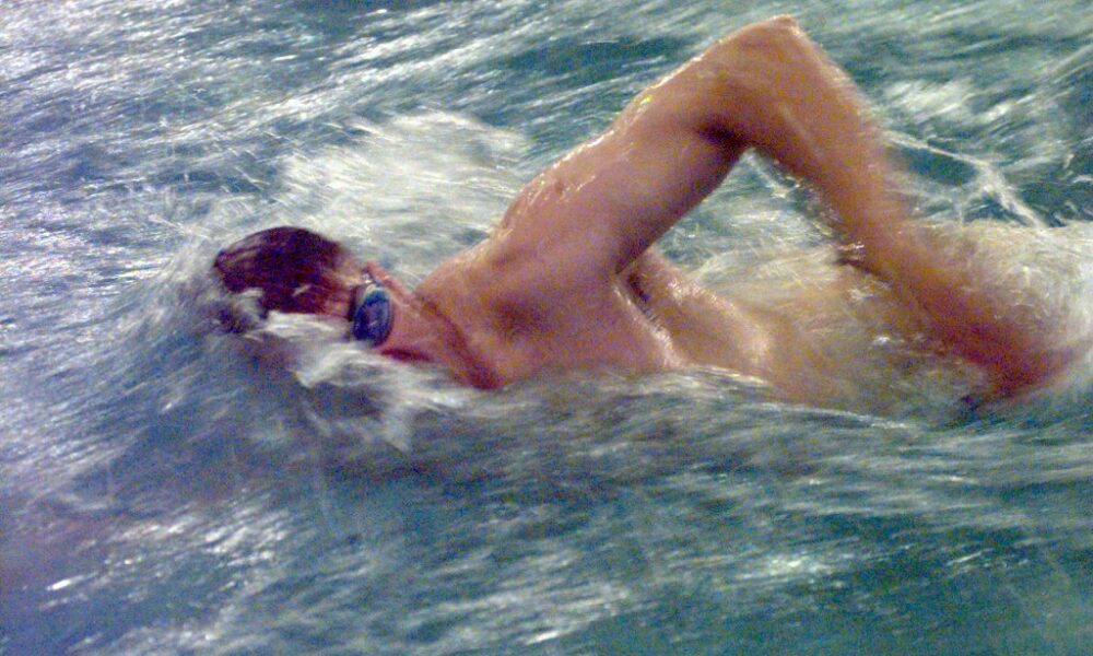 Swimmer performing the front crawl freestyle stroke, rotating the head to breathe beside an elevated recovery elbow