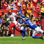 Washington Commanders player carrying the football while two New York Giants defenders pursue during their September 2025 matchup, archival game photo