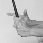 Black-and-white close-up photo of hands grasping a golf club showing finger placement