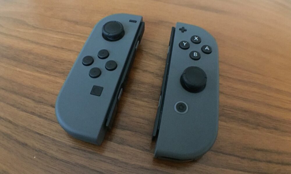 Two gray Nintendo Switch Joy-Con controllers on a table, with both thumbsticks visible