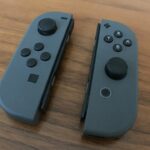 Two gray Nintendo Switch Joy-Con controllers on a table, with both thumbsticks visible