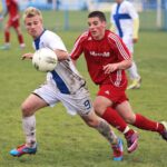 Two soccer players competing for the ball in a match