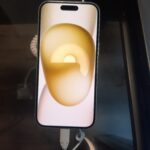 Real iPhone 15 device photographed at an Apple retailer, illustrating the device used to view saved Wi-Fi passwords