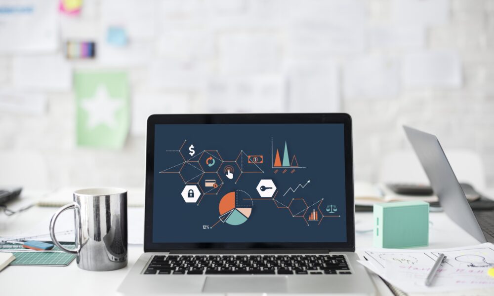 Real MacBook laptop open on a desk with charts on its screen, illustrating working with Mac windows and desktop space