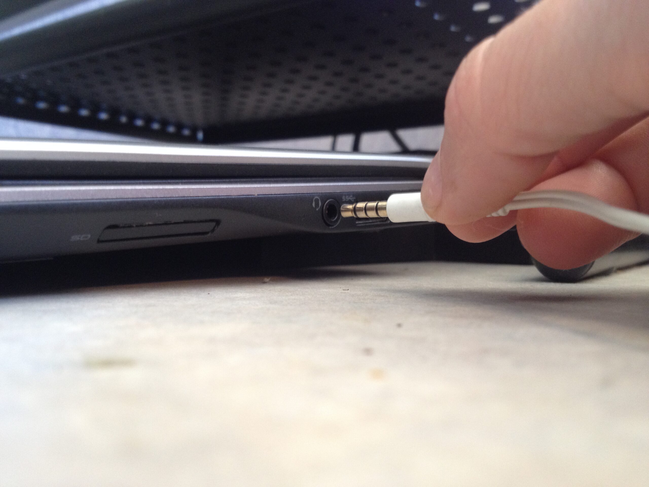 Photo of an audio microphone or headset jack being plugged into a laptop computer