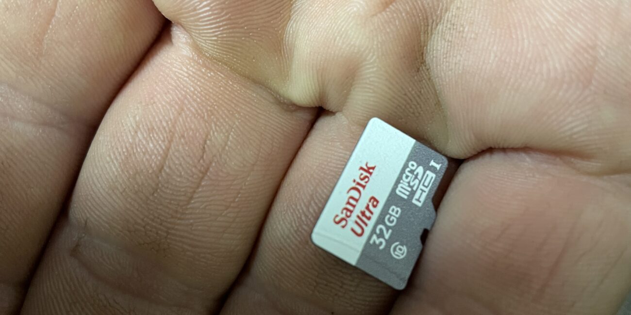 Real 32GB microSD card held in a hand, showing size of removable card storage