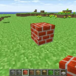 Minecraft Classic version 0.30 gameplay screenshot with brick blocks, grassy terrain and the original block hotbar