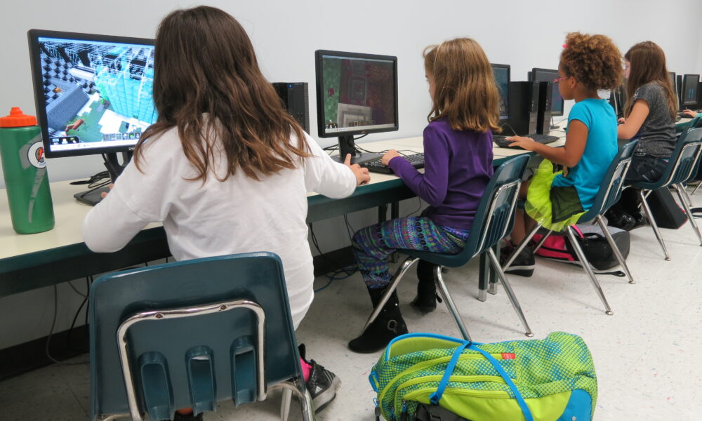 Students playing Minecraft together on computers in a classroom