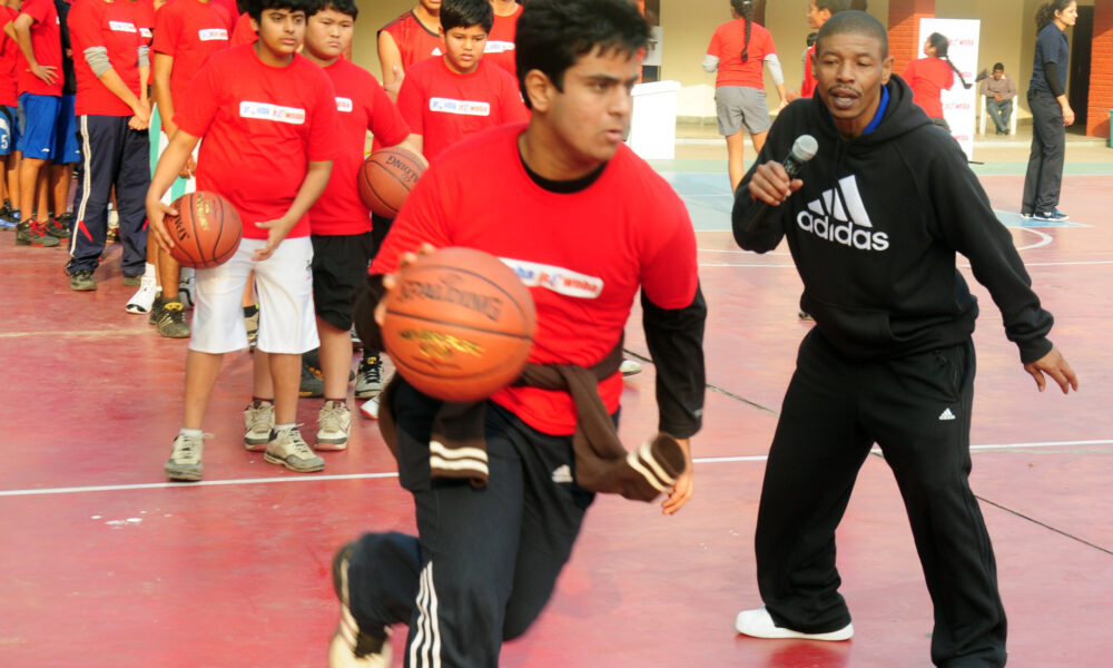 Former NBA player Muggsy Bogues coaching young players on a basketball court in 2012
