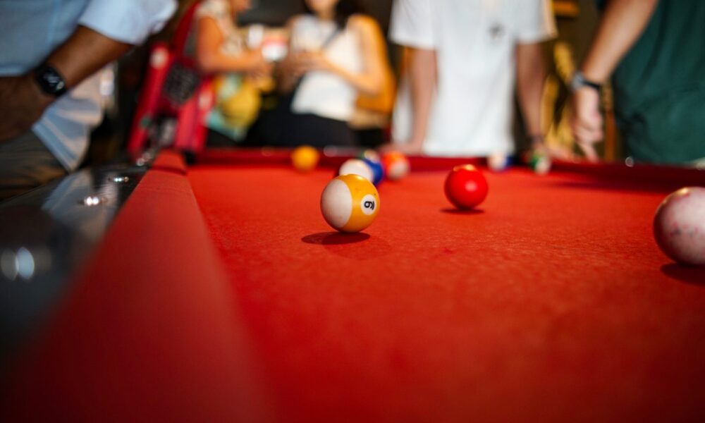 Yellow striped number nine pool ball on a red felt billiard table during a game of nine-ball