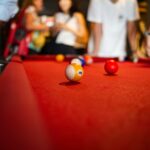 Yellow striped number nine pool ball on a red felt billiard table during a game of nine-ball