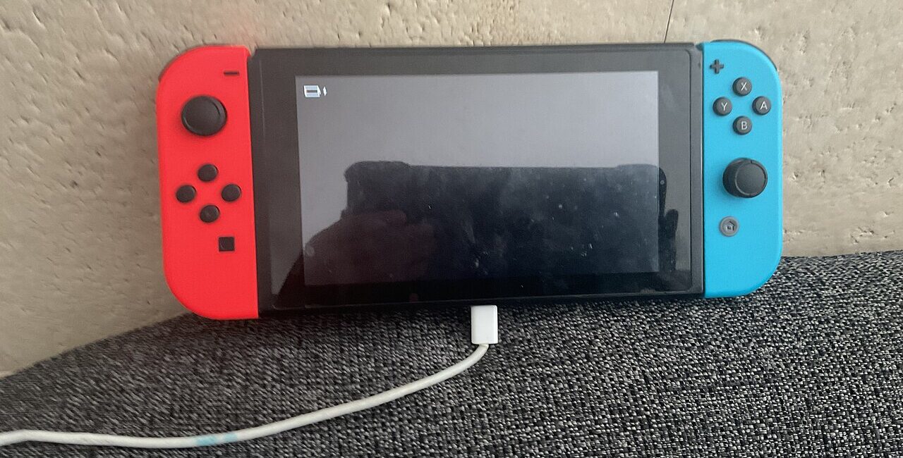 Nintendo Switch handheld gaming console resting near its charging cable