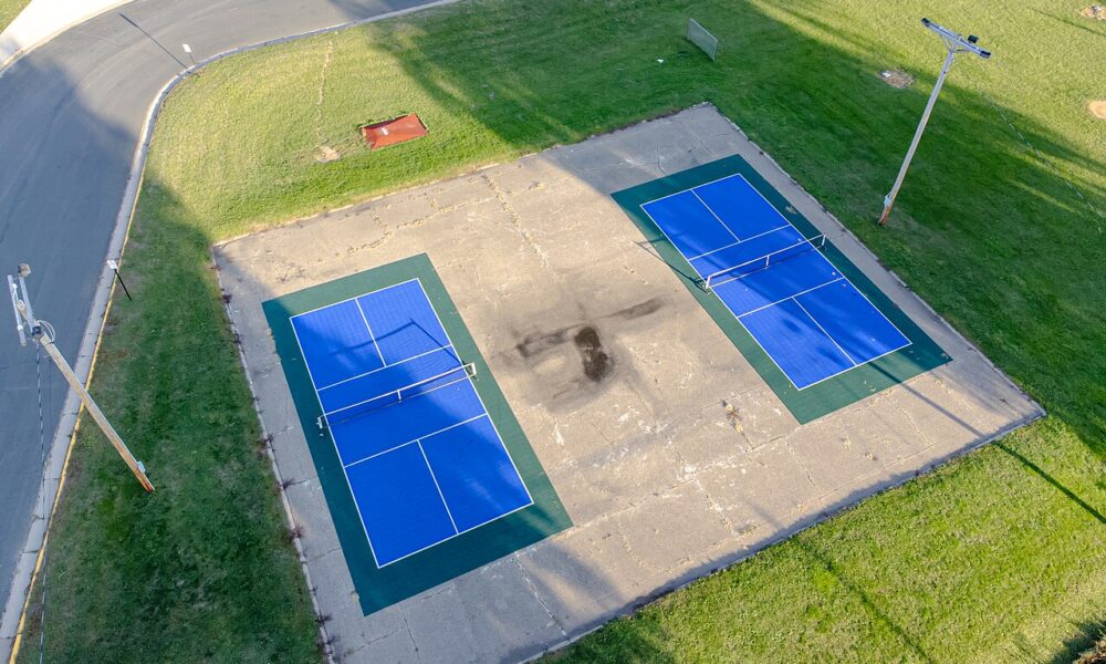 Aerial real photograph of two outdoor pickleball courts showing the seven-foot non-volley zones beside the nets