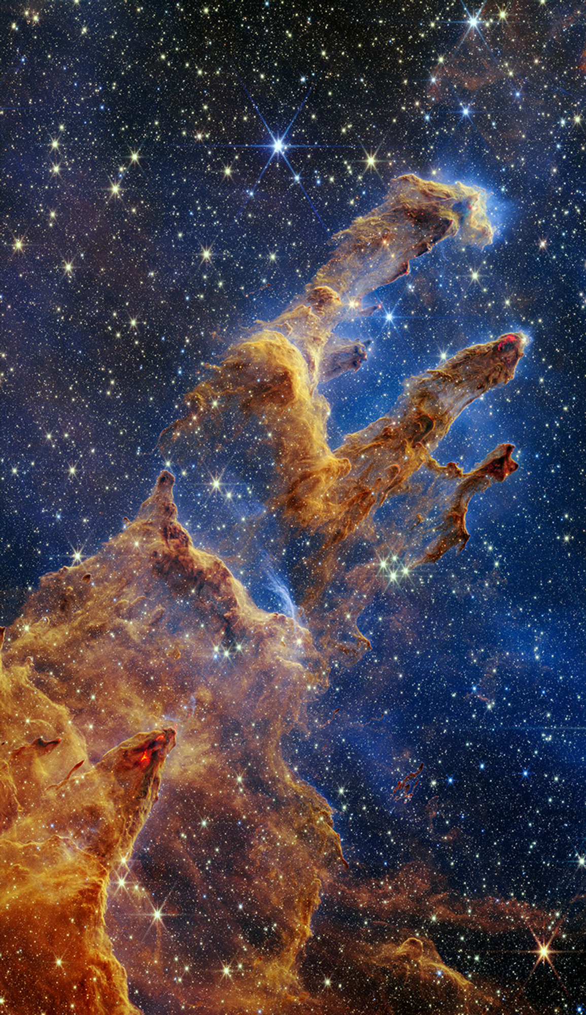 Authentic 2022 NASA Webb NIRCam photograph of Pillars of Creation showing semitransparent golden-red columns, young stars and surrounding dust