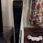 Real photo of a PlayStation 5 DualSense wireless controller next to the console