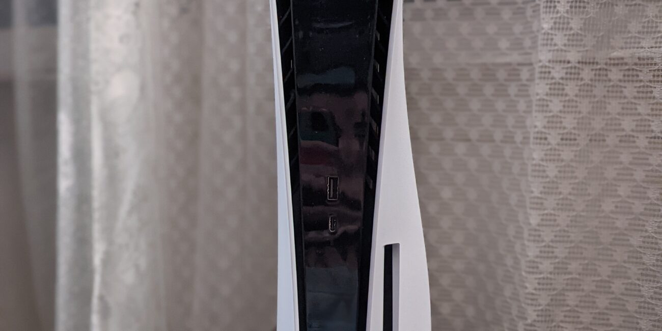 Real photograph of PlayStation 5 and DualSense controller on a light background