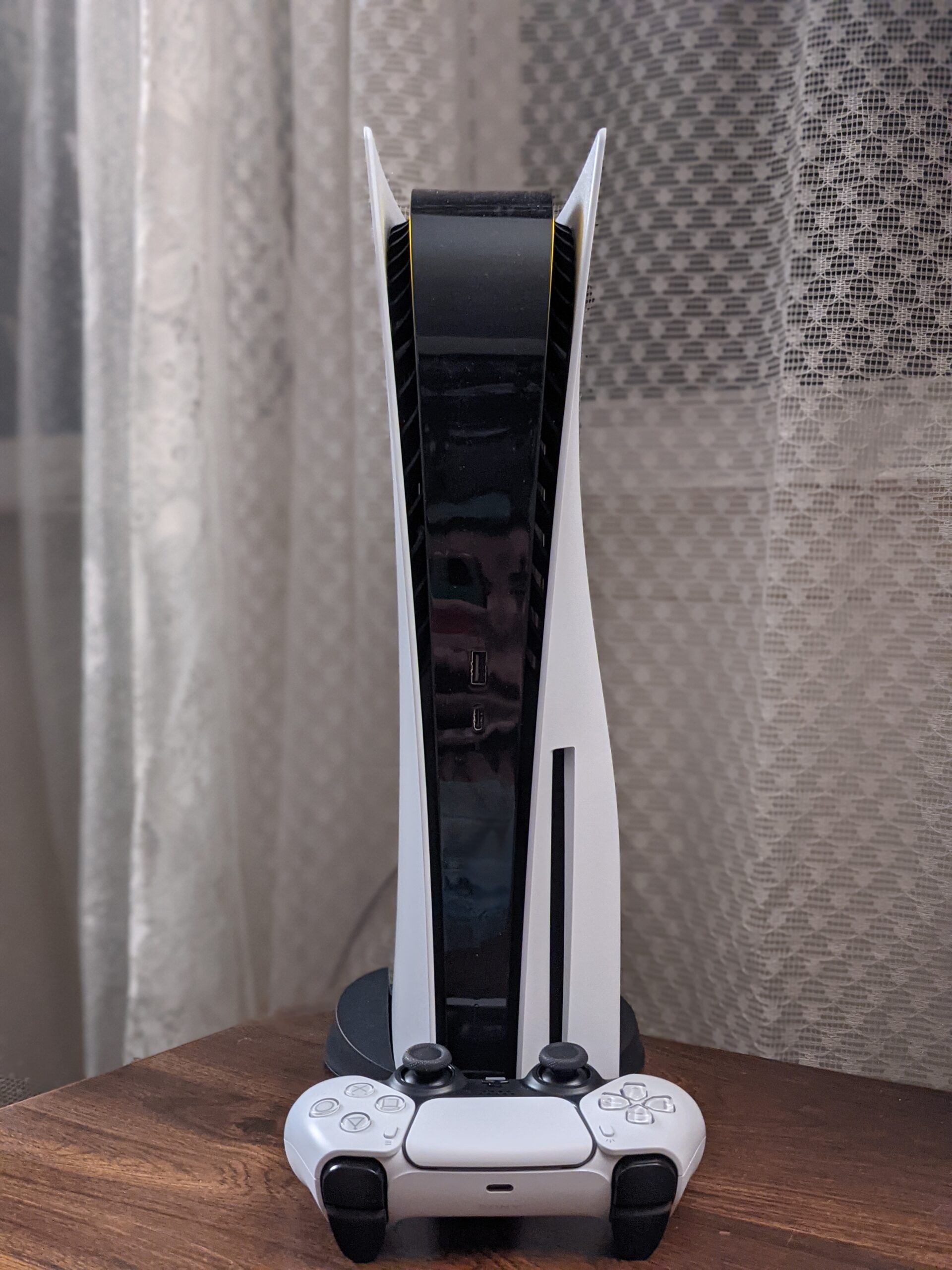 Real photograph of a PS5 console and white DualSense wireless controller