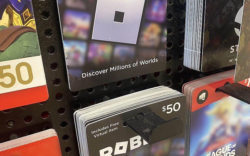 Photograph of Roblox gift cards displayed for sale in a store; paid Robux purchase illustration