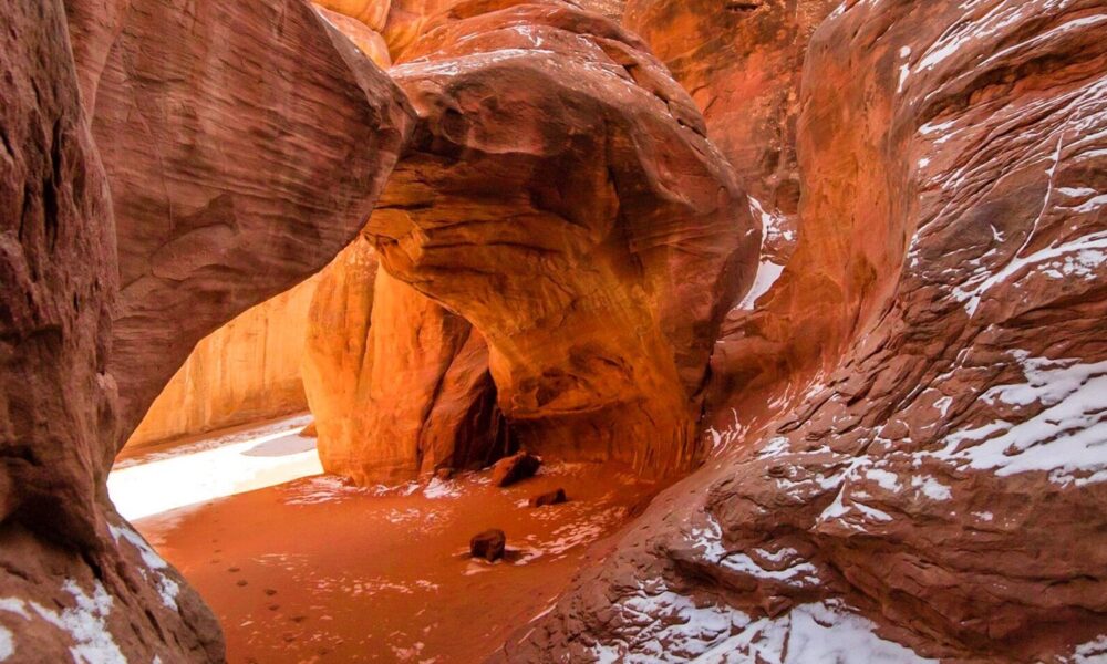 Sand Dune Arch in Arches National Park framed by sandstone fins with small patches of winter snow