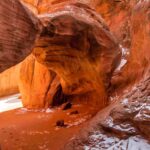 Sand Dune Arch in Arches National Park framed by sandstone fins with small patches of winter snow