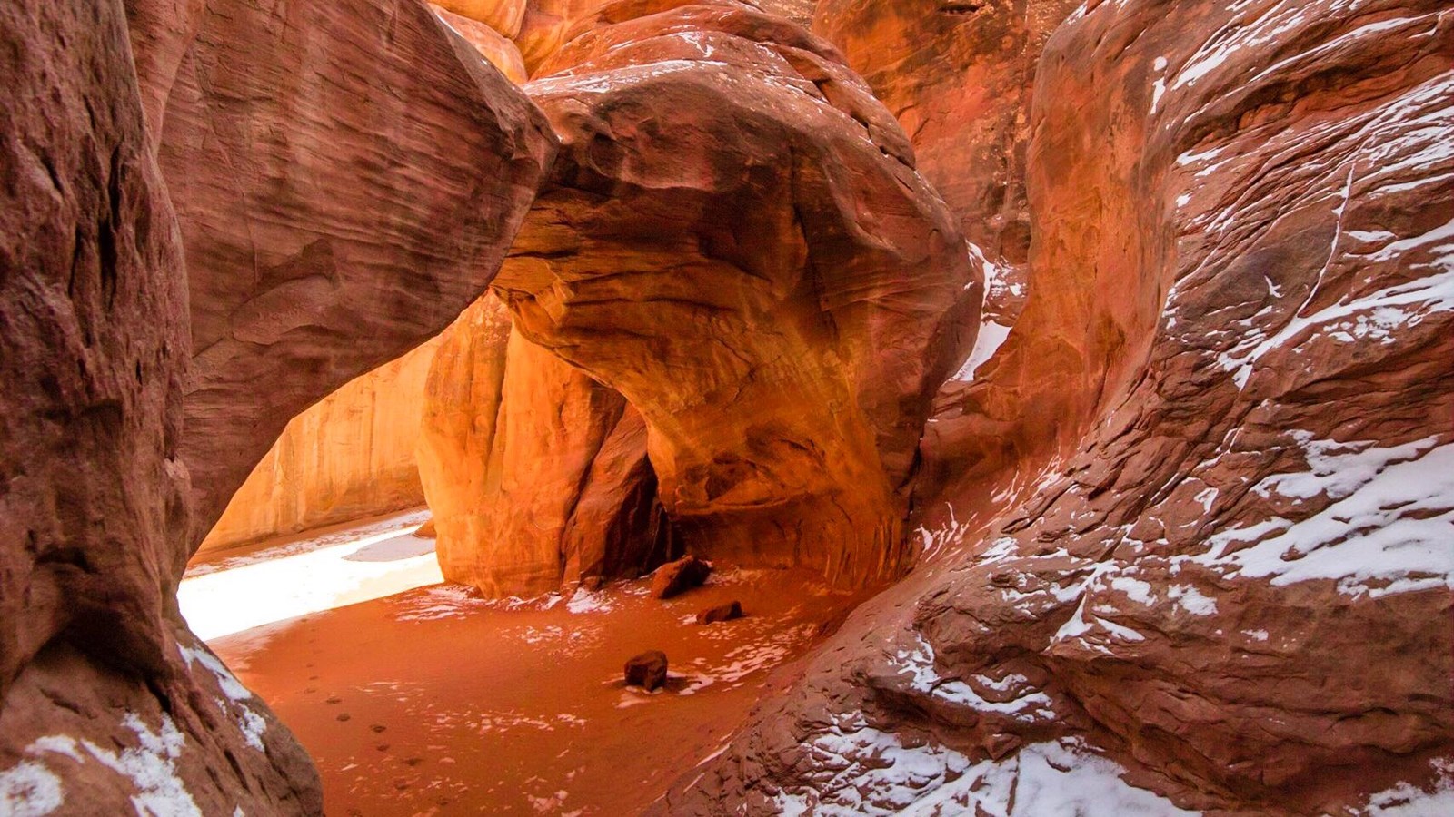 Sand Dune Arch in Arches National Park framed by sandstone fins with small patches of winter snow