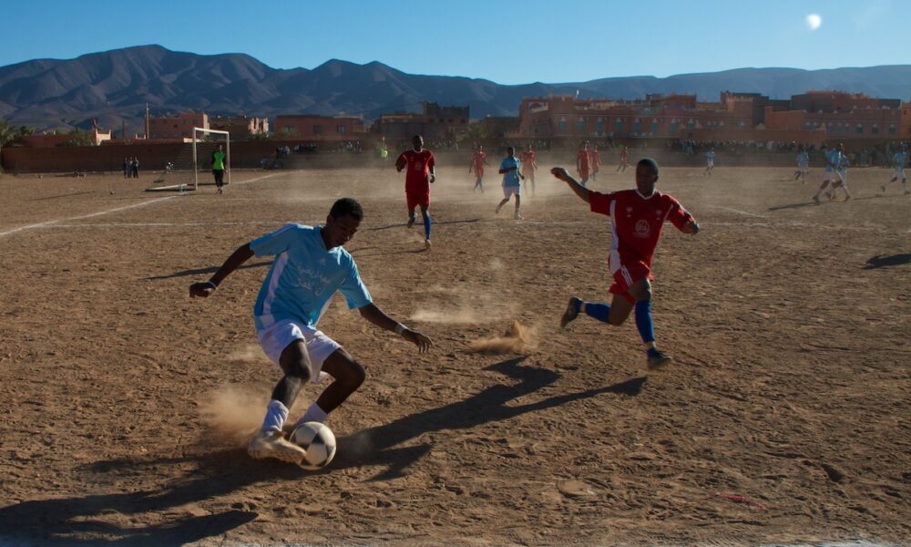 Soccer players contest possession during a match in Agdz, Morocco, illustrating off-ball attacking runs