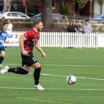 Soccer player dribbling a ball on grass during open play, illustrating false-nine movement