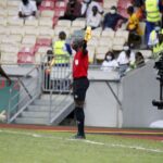 Assistant referee holding a flag during a football match, illustrating the offside rule