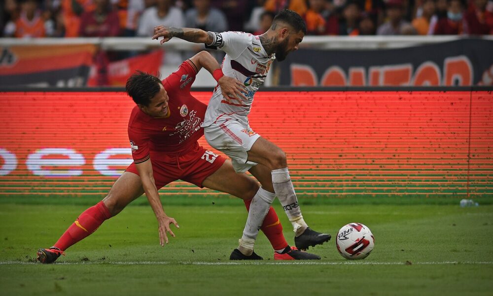 Two soccer players contesting possession in a one-versus-one defending duel