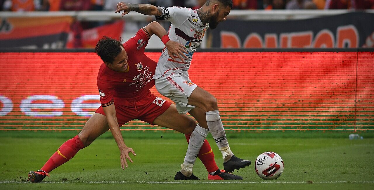 Two soccer players contesting possession in a one-versus-one defending duel