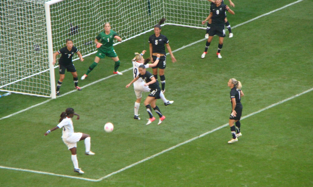 Soccer player striking the ball toward goal during a football match, demonstrating a shooting attempt