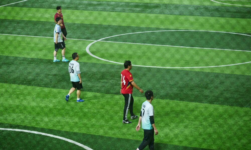 Soccer players keeping their positions across a green pitch in a match
