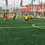 Soccer players spread across a football pitch during a recreational match in Benin