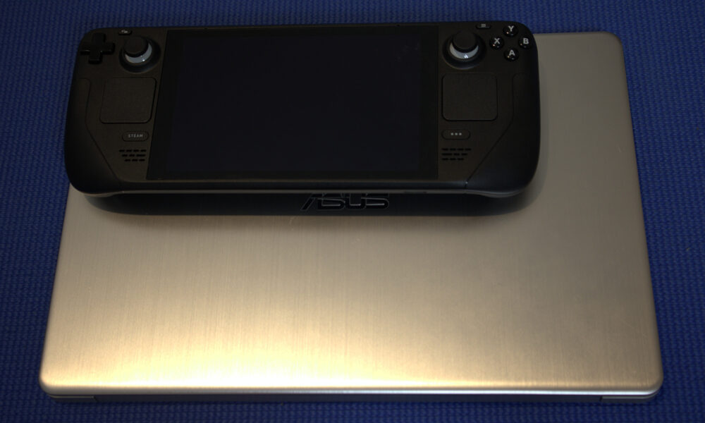 Steam Deck handheld gaming computer beside an ASUS laptop