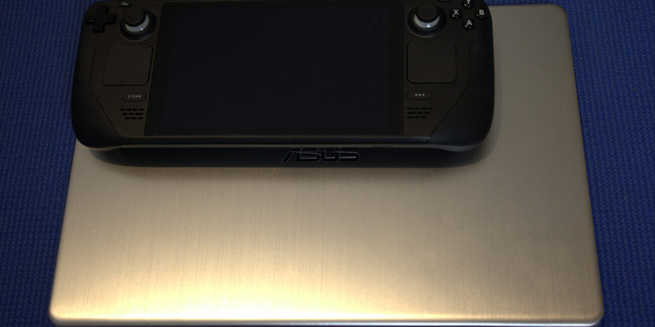 Steam Deck handheld gaming computer beside an ASUS laptop